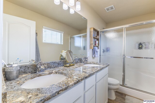 bathroom with toilet, hardwood / wood-style flooring, walk in shower, and vanity