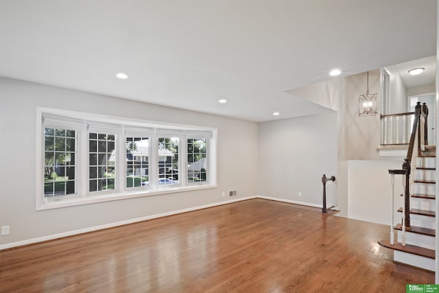 unfurnished living room with wood-type flooring and a chandelier