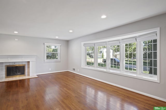 unfurnished living room with dark hardwood / wood-style floors and a tiled fireplace