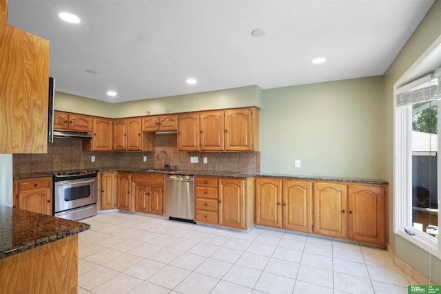 kitchen with backsplash, dark stone countertops, sink, appliances with stainless steel finishes, and light tile patterned floors