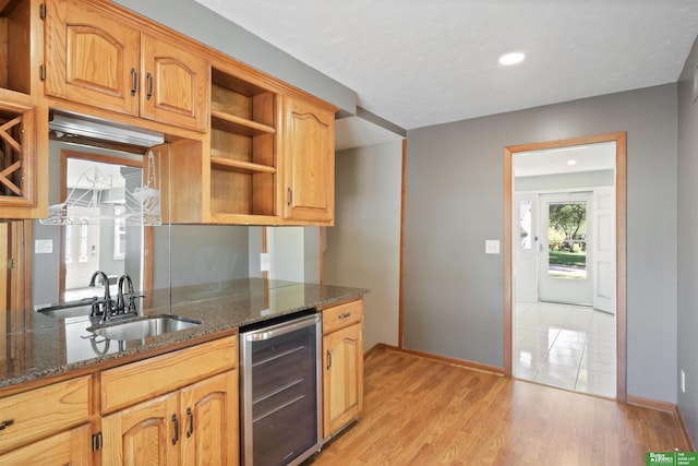 kitchen featuring light hardwood / wood-style floors, sink, beverage cooler, and dark stone counters