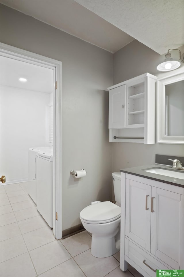 bathroom with toilet, washer and clothes dryer, tile patterned flooring, and vanity