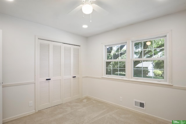 unfurnished bedroom with ceiling fan, light colored carpet, and a closet