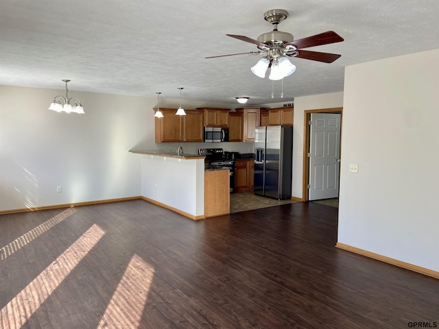 kitchen with kitchen peninsula, appliances with stainless steel finishes, decorative light fixtures, dark wood-type flooring, and ceiling fan with notable chandelier