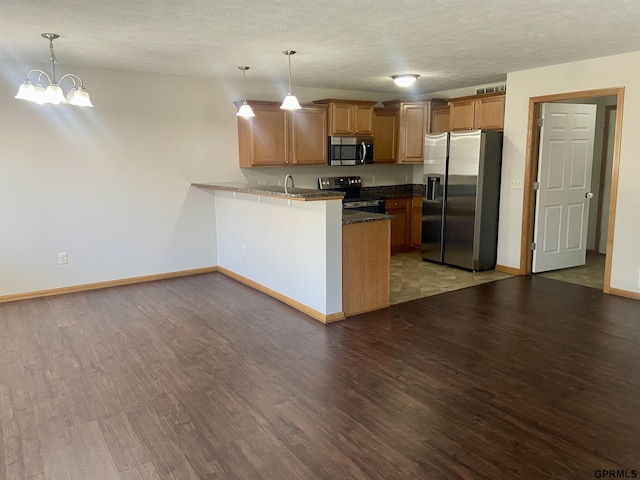 kitchen featuring decorative light fixtures, appliances with stainless steel finishes, dark hardwood / wood-style flooring, and kitchen peninsula