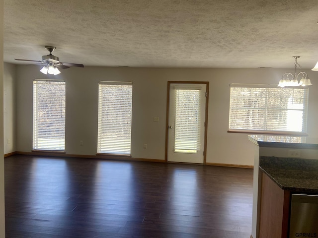 unfurnished living room with dark hardwood / wood-style flooring, ceiling fan with notable chandelier, and a textured ceiling