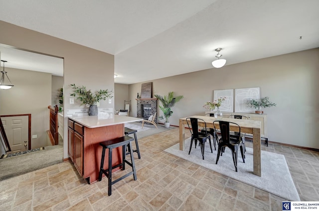 kitchen with hanging light fixtures, kitchen peninsula, a fireplace, and a kitchen breakfast bar