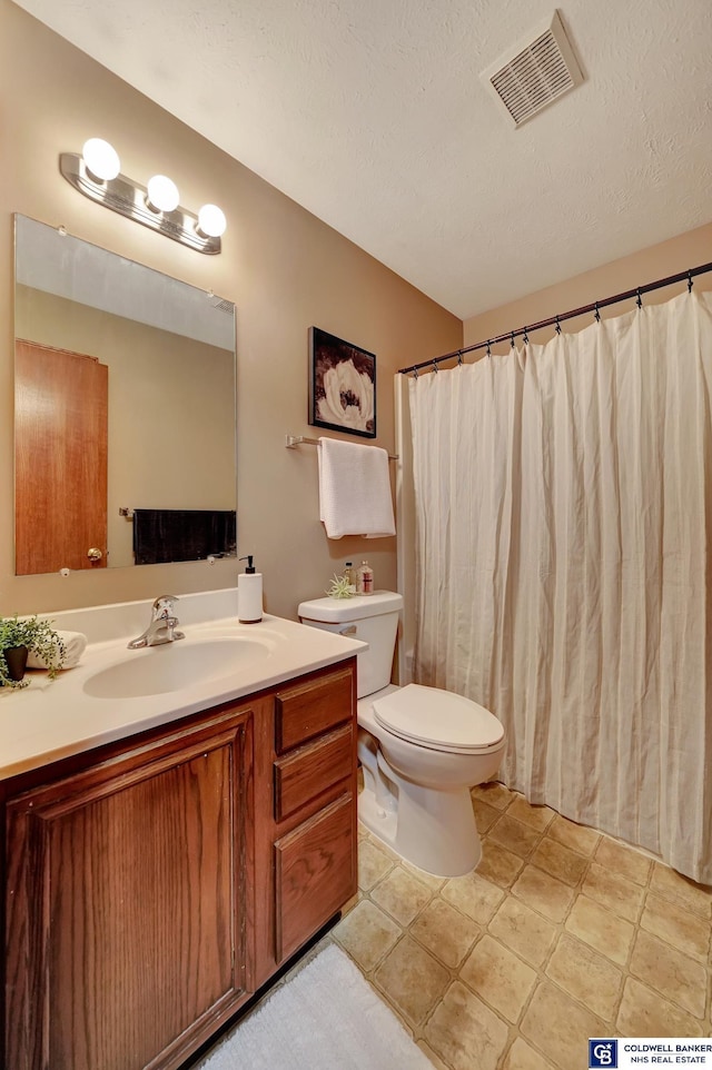 bathroom with toilet, vanity, and a textured ceiling