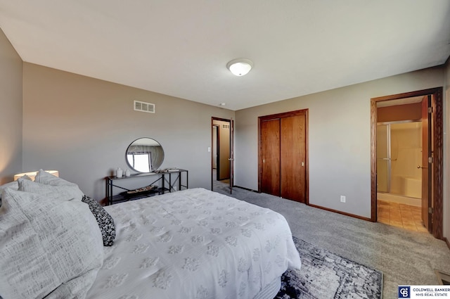 carpeted bedroom with a closet and ensuite bath