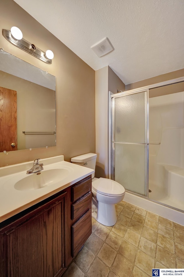 bathroom featuring toilet, vanity, walk in shower, and a textured ceiling