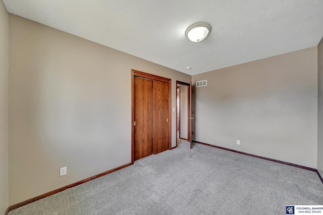 unfurnished bedroom with a closet and light carpet