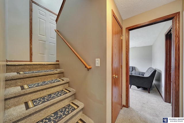 stairs with carpet floors and a textured ceiling