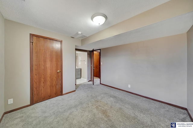 unfurnished bedroom featuring a textured ceiling, a closet, and light carpet