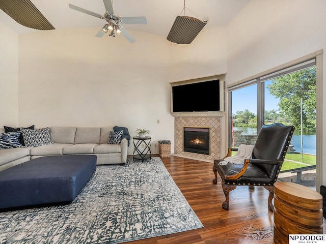 living room with dark wood-type flooring, ceiling fan, a fireplace, and high vaulted ceiling