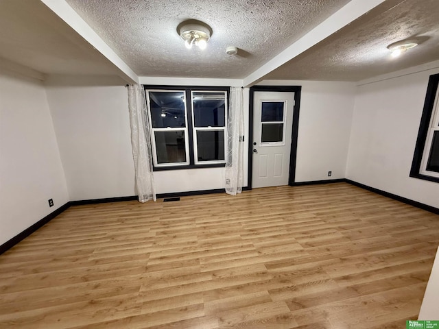 spare room with a textured ceiling and light hardwood / wood-style floors