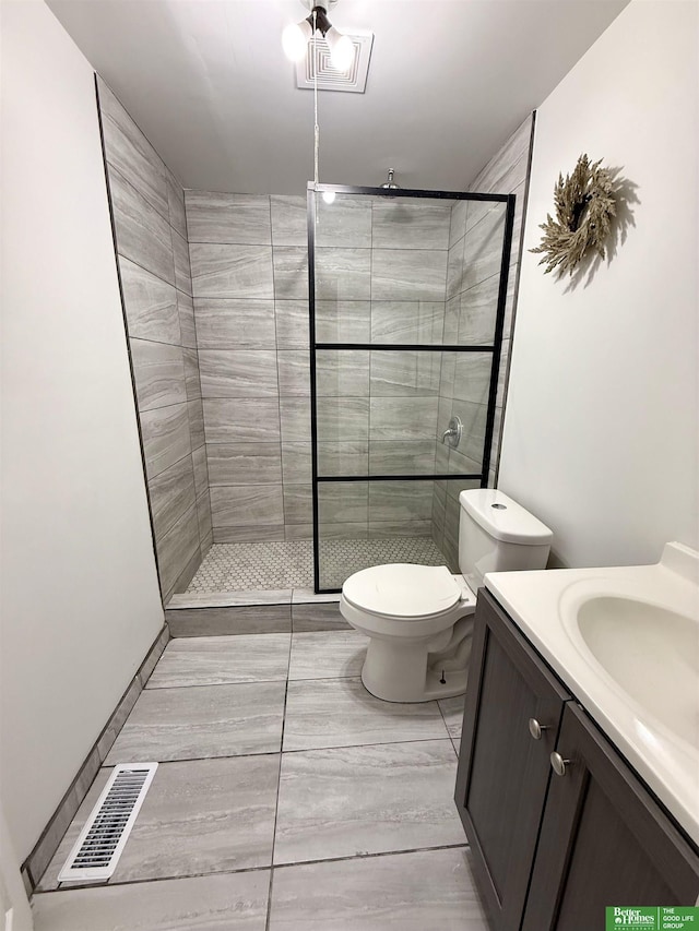 bathroom with toilet, vanity, and tiled shower