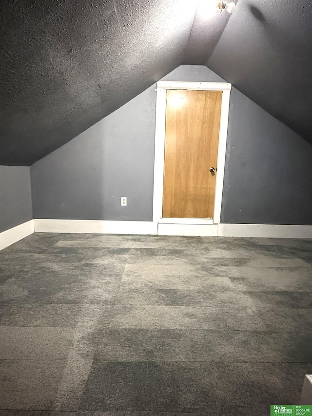 bonus room featuring dark carpet, a textured ceiling, and lofted ceiling