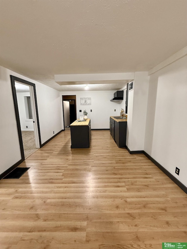 kitchen with exhaust hood, sink, light hardwood / wood-style floors, and a center island