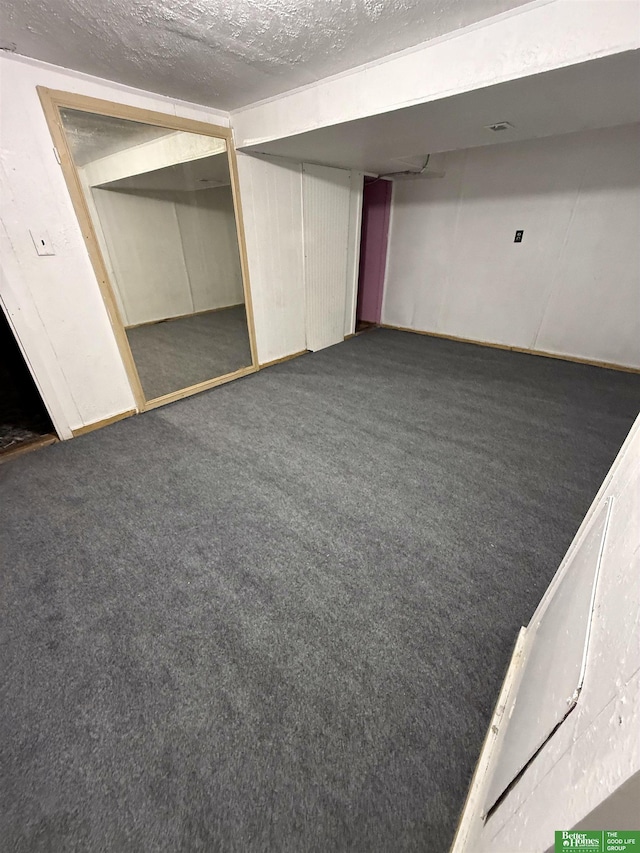 basement with a textured ceiling and dark colored carpet