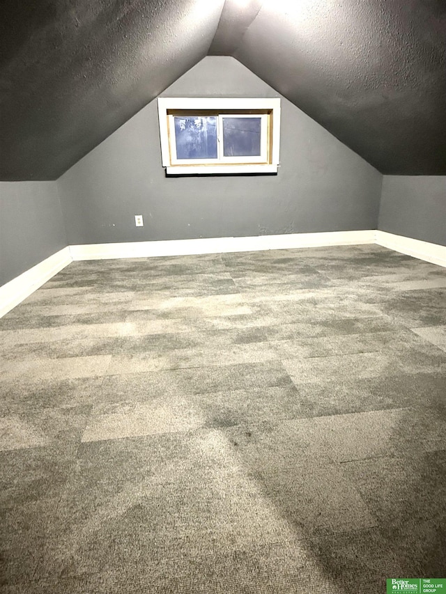 additional living space featuring carpet floors, vaulted ceiling, and a textured ceiling