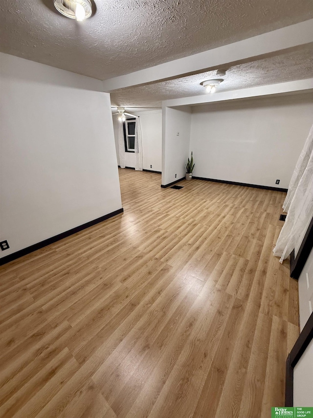 unfurnished room with light wood-type flooring and a textured ceiling