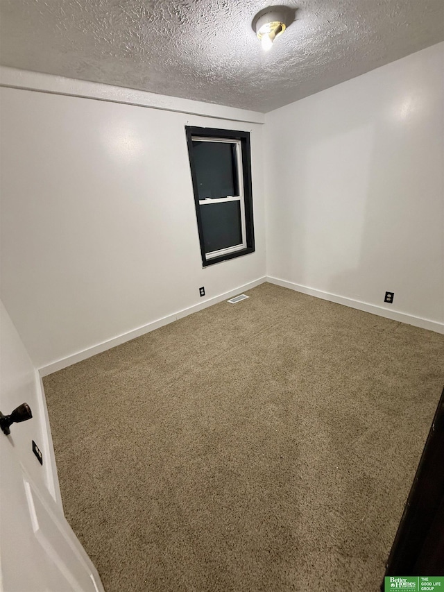 carpeted empty room featuring a textured ceiling