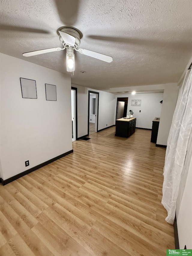 interior space featuring a textured ceiling, ceiling fan, and light hardwood / wood-style flooring