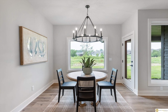 dining area with light wood-type flooring and an inviting chandelier