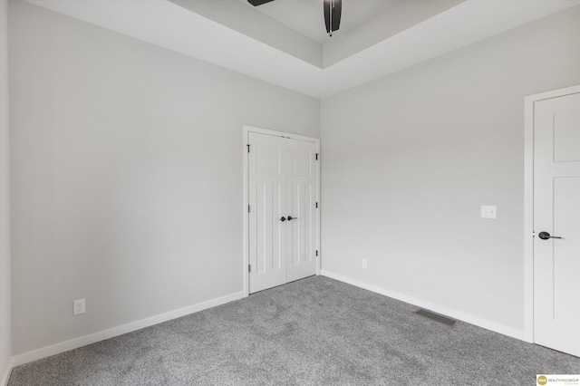 carpeted empty room featuring ceiling fan and a tray ceiling