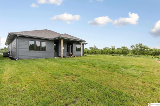 back of property with central AC unit and a yard