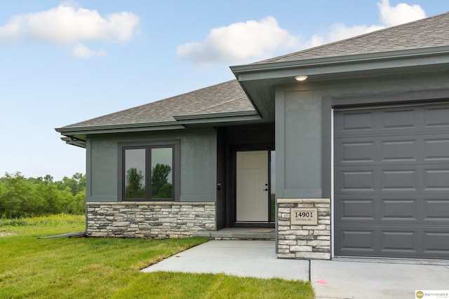 view of exterior entry with a garage and a yard