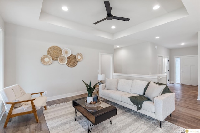 living room featuring ceiling fan, hardwood / wood-style floors, and a raised ceiling