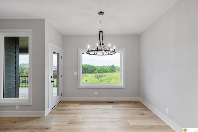 unfurnished dining area with an inviting chandelier and light hardwood / wood-style floors