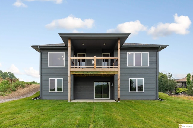 rear view of house with a balcony, a yard, and a patio