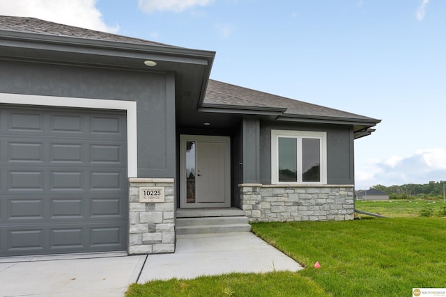 doorway to property with a garage and a lawn