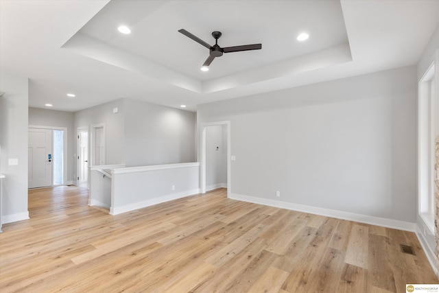 spare room with ceiling fan, light hardwood / wood-style flooring, and a raised ceiling