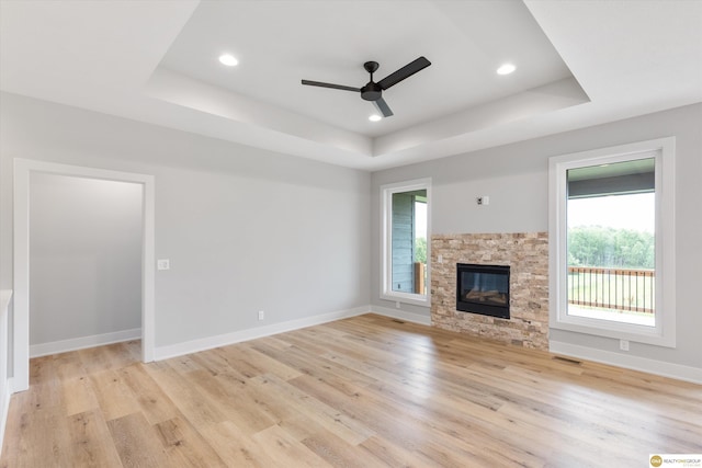 unfurnished living room featuring a fireplace, a raised ceiling, and a healthy amount of sunlight