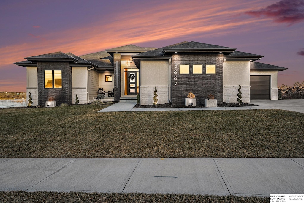 prairie-style house featuring a garage and a lawn