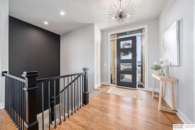 foyer entrance featuring wood-type flooring and a chandelier