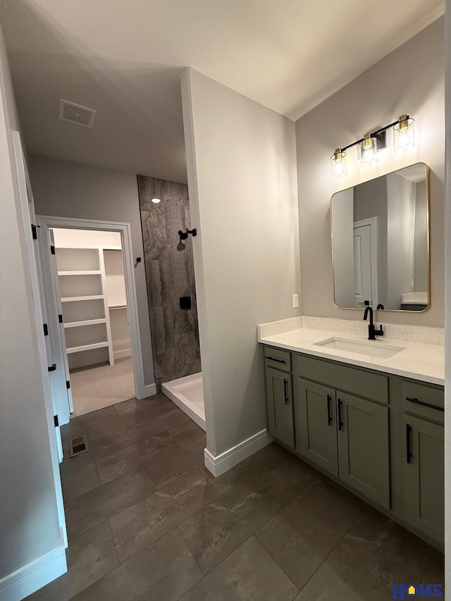 bathroom featuring tiled shower and vanity