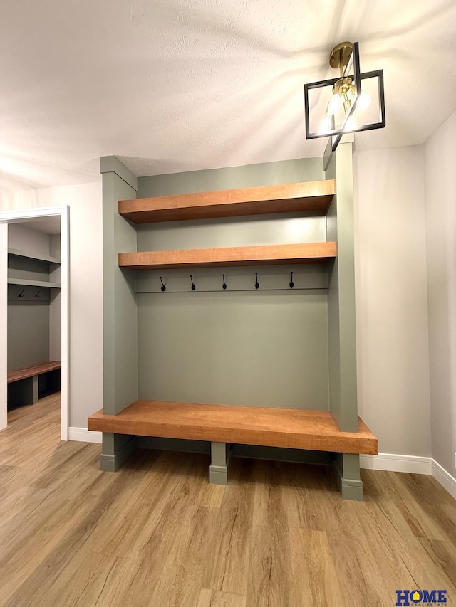 mudroom with light wood-type flooring and a textured ceiling