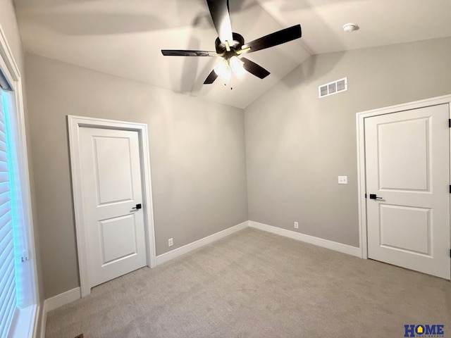 spare room with ceiling fan, light colored carpet, and vaulted ceiling