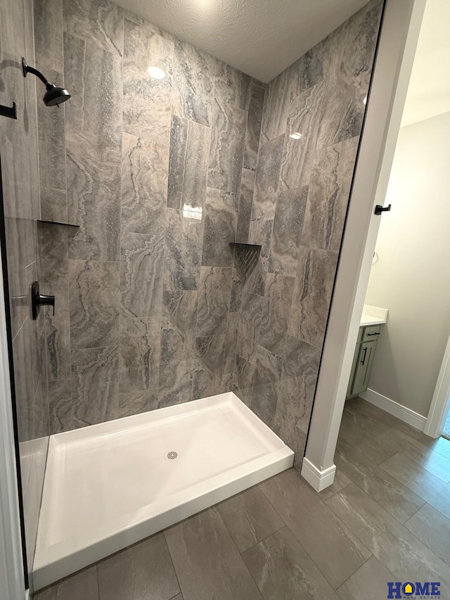 bathroom featuring a textured ceiling, a shower, and vanity