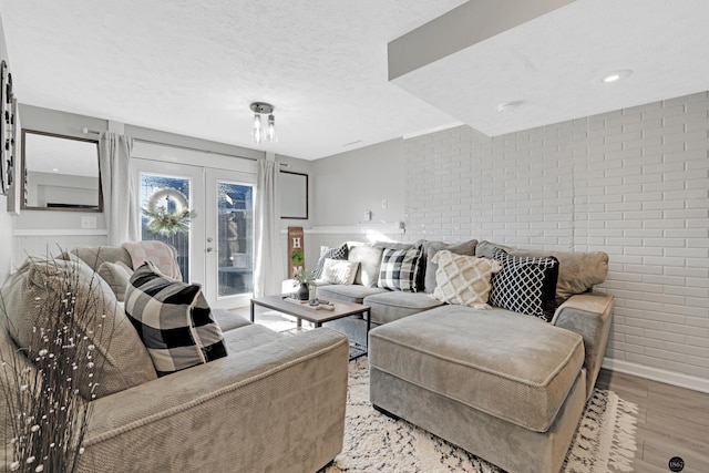 living room with brick wall, light hardwood / wood-style floors, and french doors