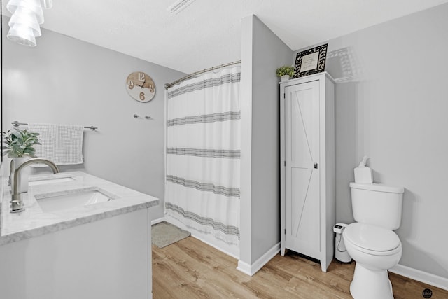 bathroom with hardwood / wood-style flooring, a textured ceiling, toilet, and vanity