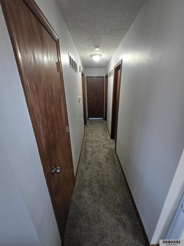 corridor featuring a textured ceiling and light colored carpet