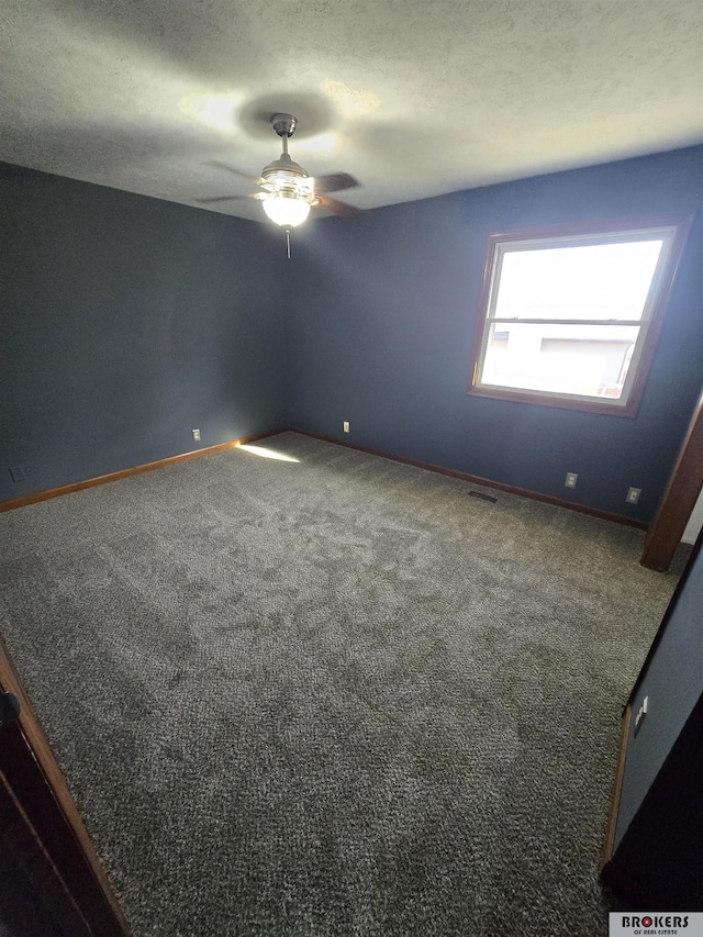 carpeted empty room featuring ceiling fan and a textured ceiling