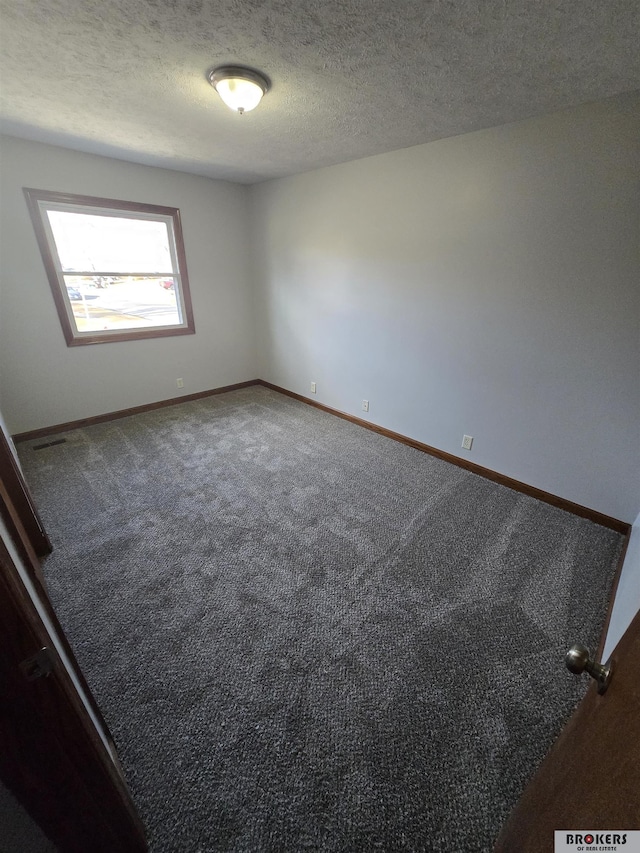 empty room with a textured ceiling and carpet flooring