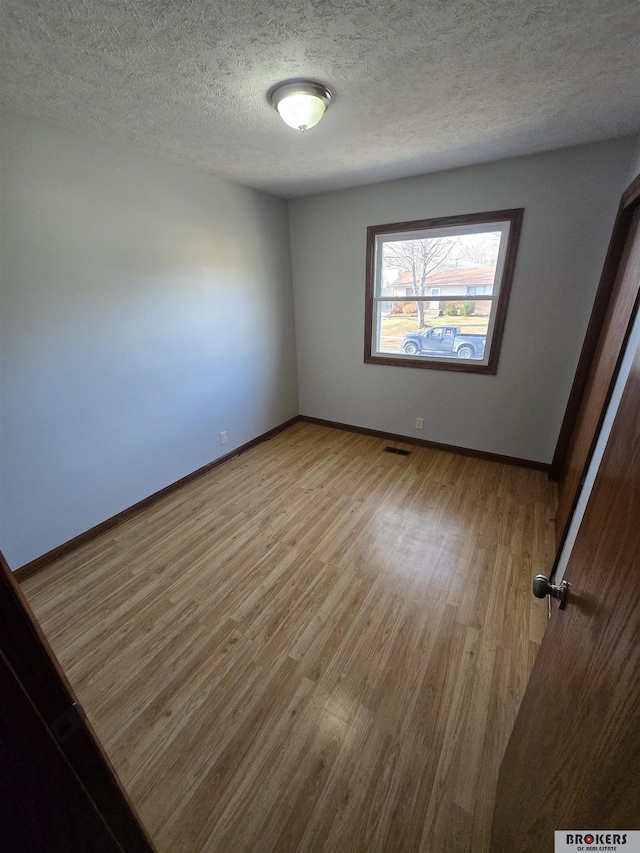 empty room featuring light wood-type flooring and a textured ceiling