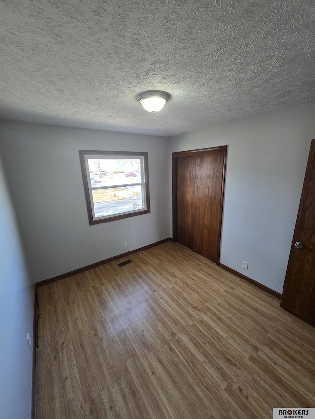 unfurnished bedroom featuring hardwood / wood-style floors, a closet, and a textured ceiling